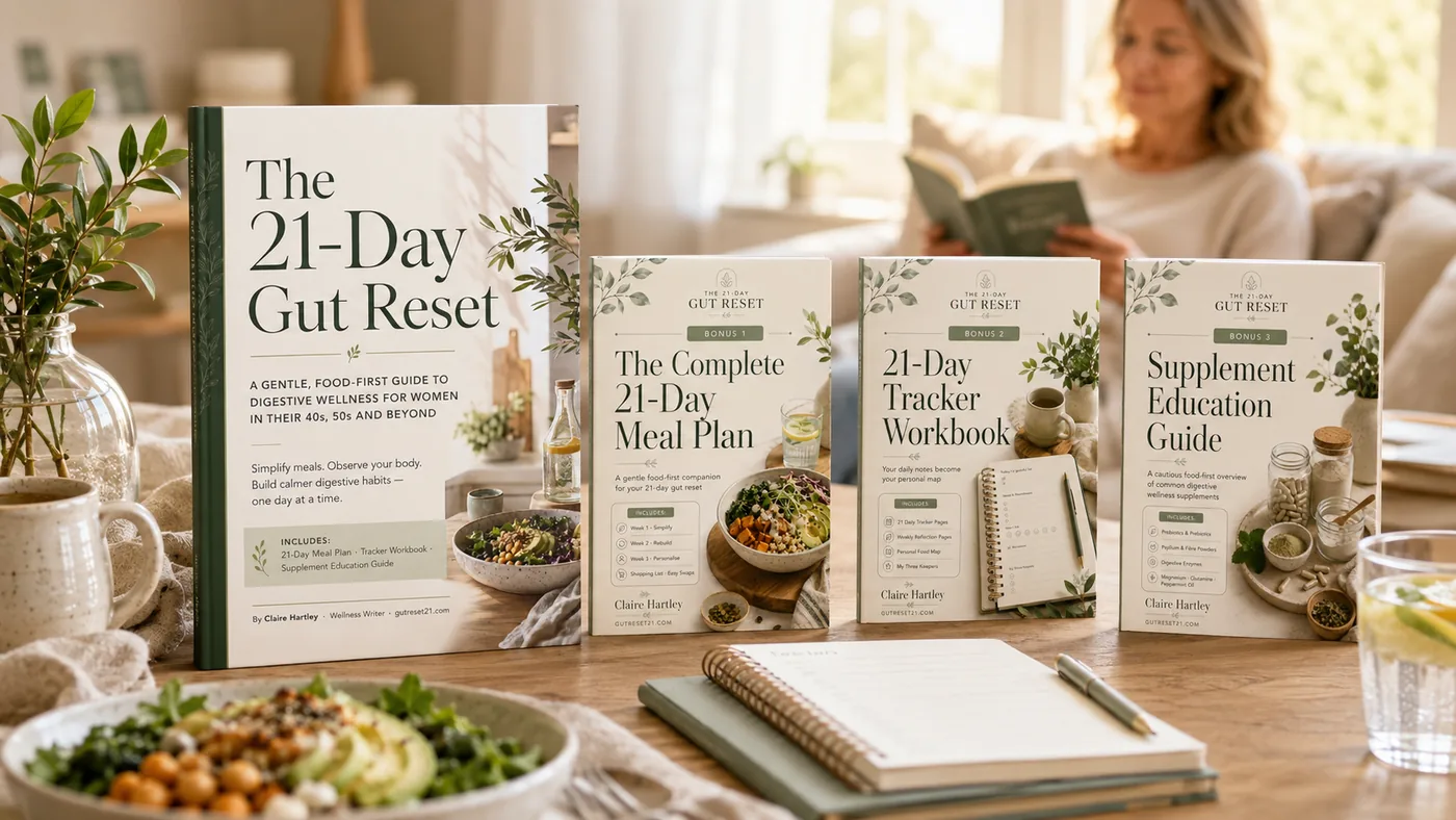 The 21-Day Gut Reset book with its 3 bonus guides — The Complete 21-Day Meal Plan, 21-Day Tracker Workbook and Supplement Education Guide — by Claire Hartley, shown on a table in a cosy living room